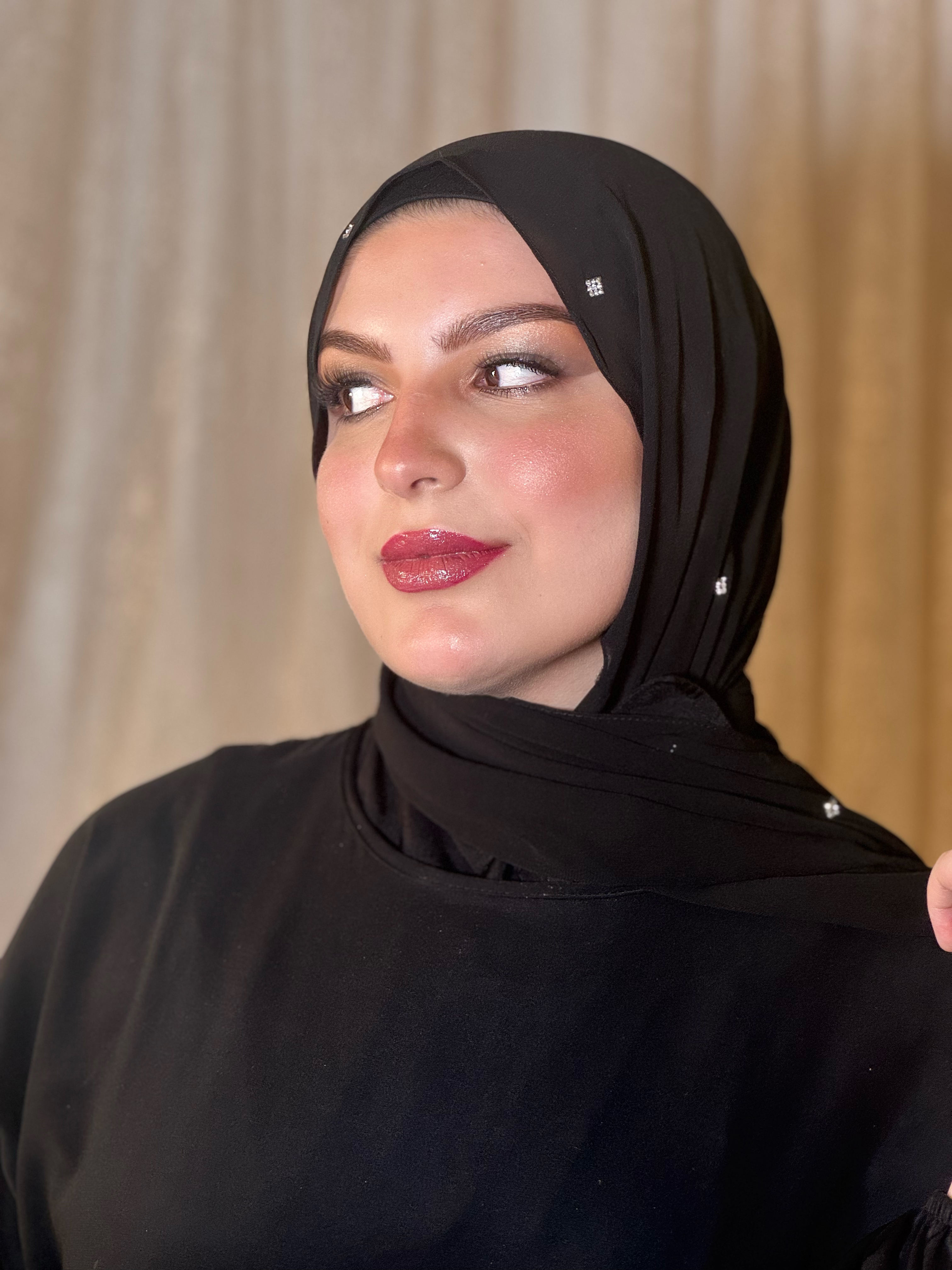Bold makeup with defined eyes and deep red glossy lips in black hijab